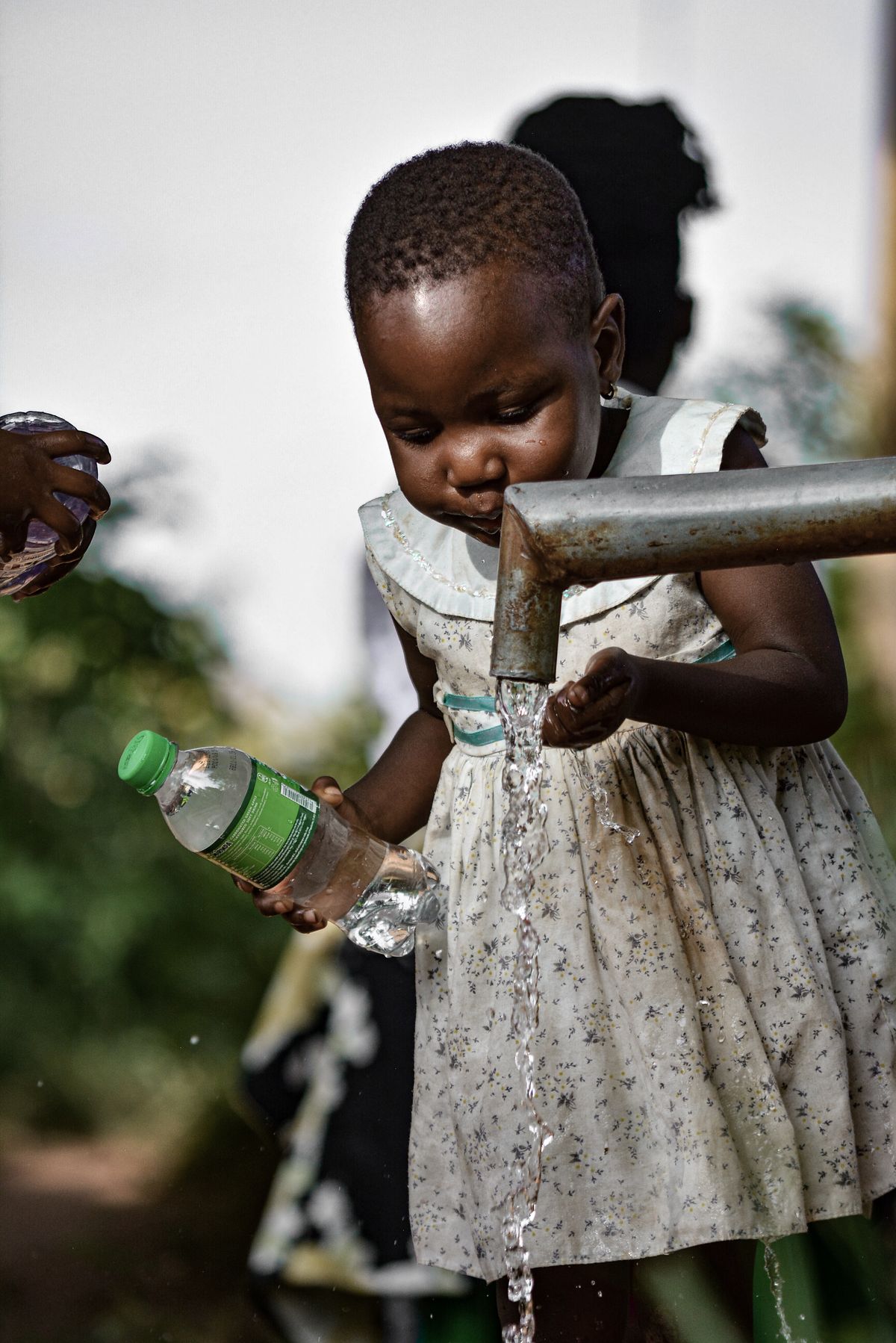 A girl collects clean water from a tap, Kampala, Uganda
